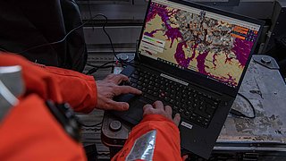Ein Wissenschaftler:innen arbeitet am Computer während des Fluges mit Satellitendaten.